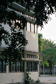 An empty school yard with a basketball court and classrooms.