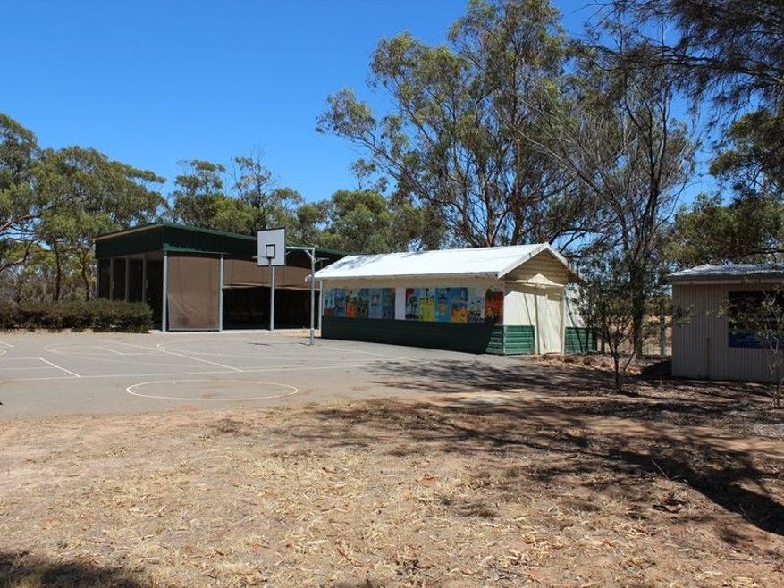 An empty school yard with a basketball court and classrooms.