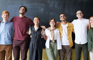 A group of teachers arm in arm in front of a blackboard.