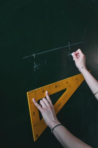 A protactor against a blackboard used to measure a line.