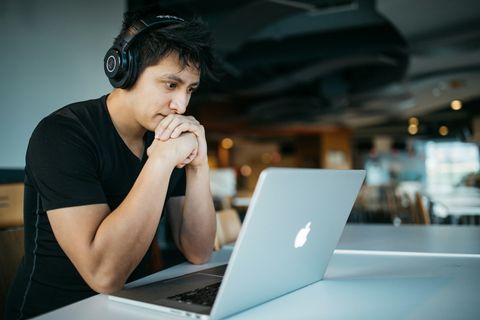 A student wearing headphones concentrating on a laptop