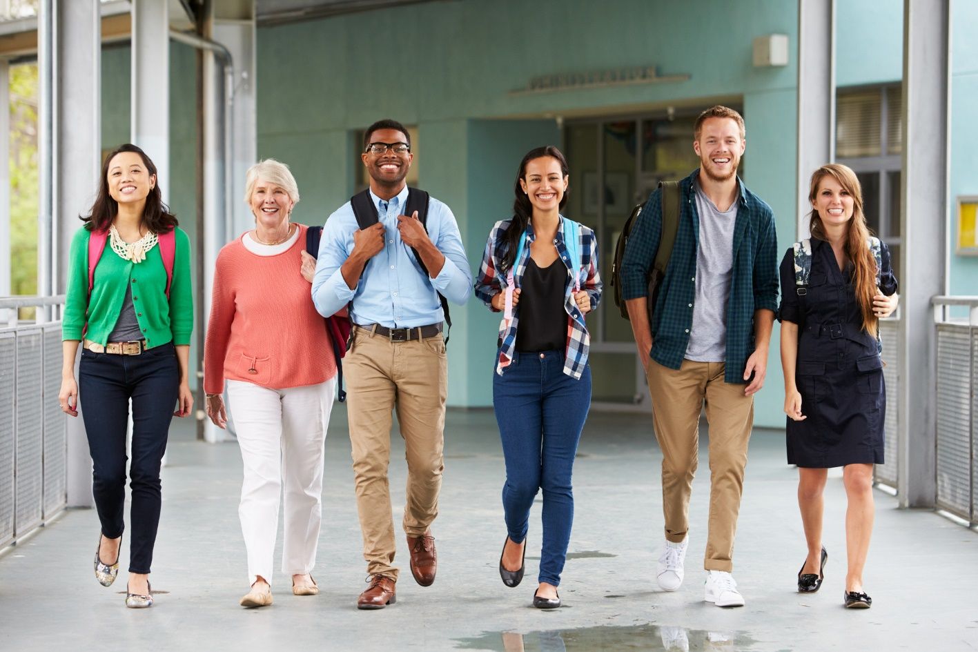 Diverse group of teachers walking outside a school.